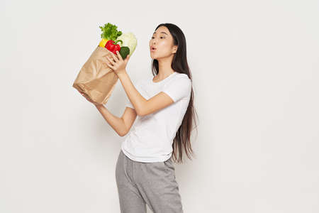 Slender woman in sportswear holds in her hand a packet with vegetables calorieの写真素材