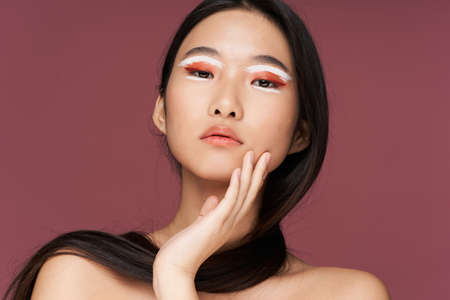 Beautiful brunette with evening make-up on a pink backgroundの写真素材