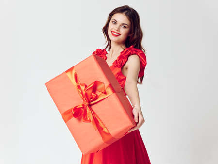 Charming woman with red box in hands on isolated background birthday holidaysの写真素材