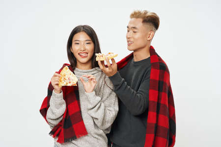 happy young people with slices of pizza and a warm plaidの写真素材