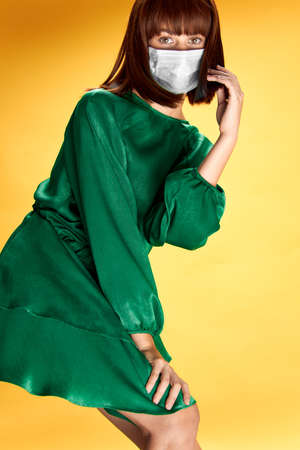 Woman in fashion dress posing in medical mask virus covid-19の写真素材