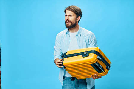 confident man with a yellow suitcase looks away and travelの写真素材
