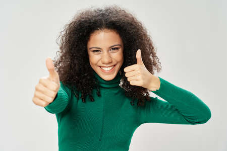 A happy woman in a green sweater smiles at the camera