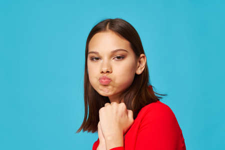 Emotional girl in a red shirt pouted lips and looks