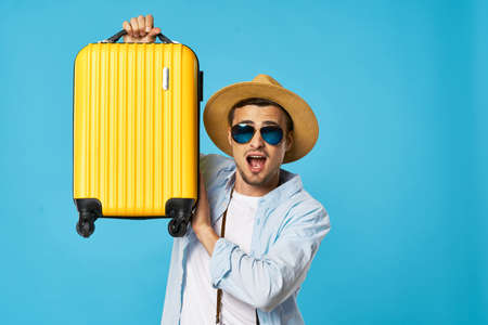man on a blue background with glasses and a yellow suitcase