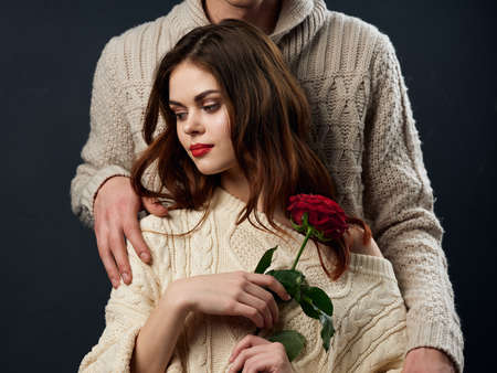 a man in a sweater and a woman with a red flower