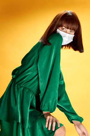 Woman in fashion dress posing in medical mask virus covid-19の写真素材