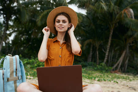Traveler on the island laptop on the lap Traveler on the island with a backpack and working