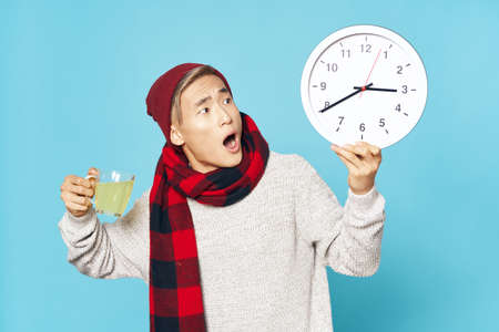 Surprised guy with a watch and a mug with a drinkの写真素材