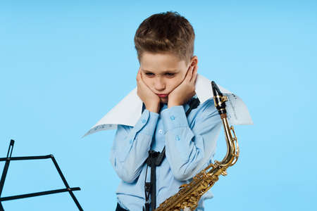 upset boy with saxophone and music bookの写真素材