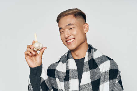 Health problem Asian man in a plaid plaid contains garlic in the hands of headacheの写真素材