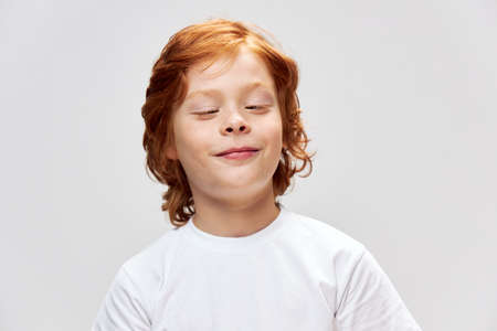 A cheerful boy looks at us on a white T-shirt grimace