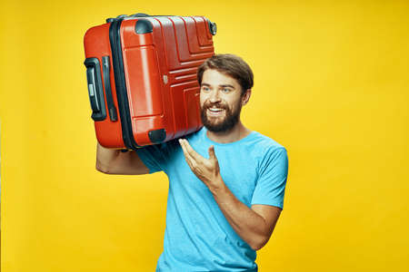 suitcase in hand happy traveler laughing yellow backgroundの写真素材