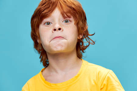 Surprised child with red hair in a yellow T-shirtの写真素材