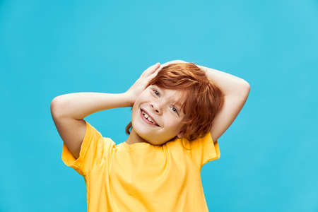 red-haired child holds his hands near his face and bent over to the side iの写真素材