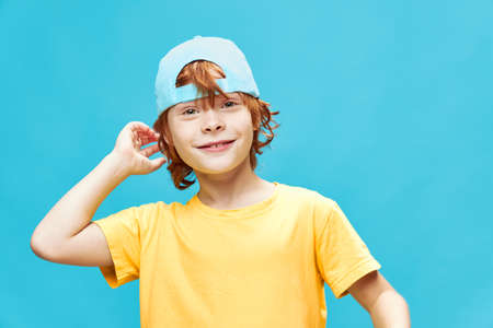 Boy in a blue cap on an isolated background red hair