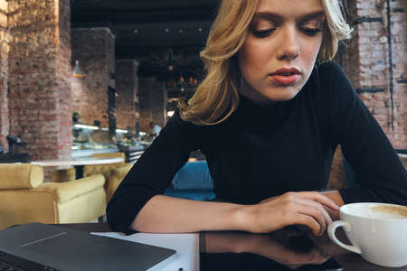 blonde woman at table in cafe coffee cup fashion interior indoor