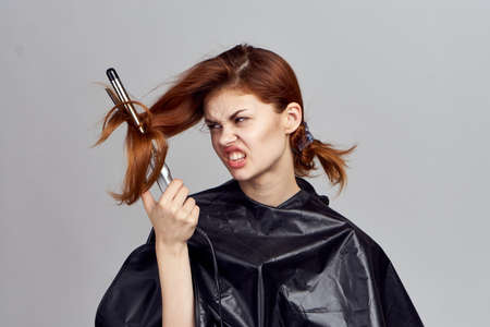 Woman in black peignoir curling iron in hand hair care comb fashionable hairstyleの写真素材