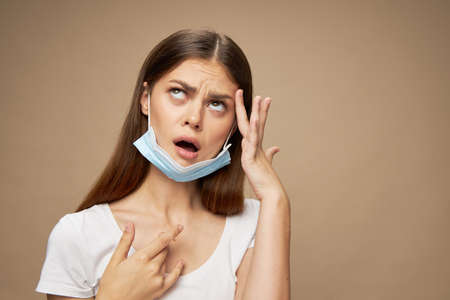 An interested woman with a medical mask on her ears looks up