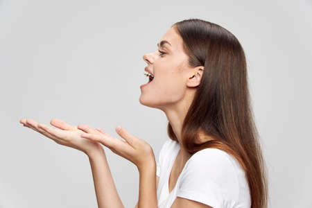 brunette woman on isolated background shows hands to the side