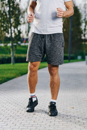 sports man in sneakers shorts and a t-shirt running in the park outdoors fitness