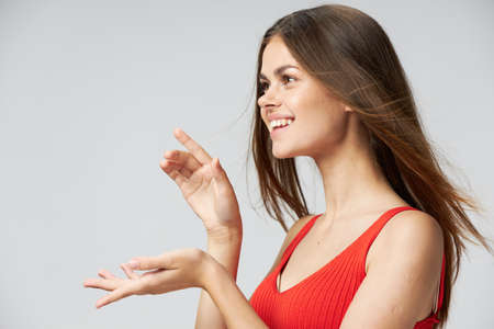 Side view of a happy woman in a red T-shirt shows her hand forward