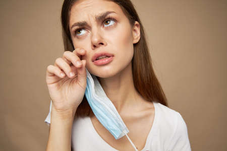 A woman in a medical jersey looks puzzled up and wipes her face