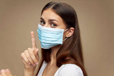 Girl in medical mask holds index finger near health