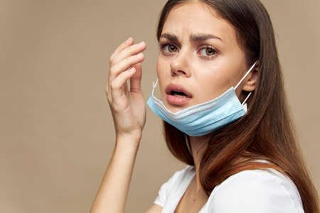 Beautiful woman with a medical mask on her face a frightened look emotions