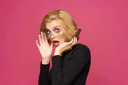 Pretty woman in black sweater short hairstyle glasses pink isolated background