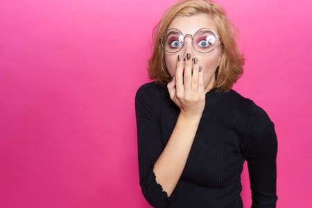 Pretty woman in black sweater red lips in glasses emotions pink backgroundの写真素材