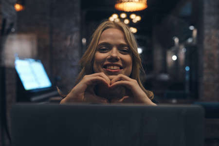 Happy woman with laptop in restaurant front view bright light emotions