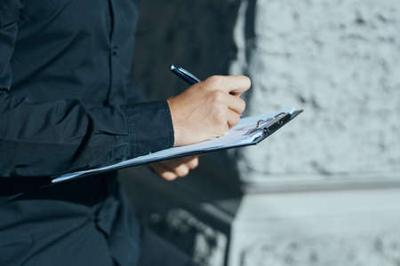 A man with documents in their hands in their black shirts on the street with a pen in his handの写真素材