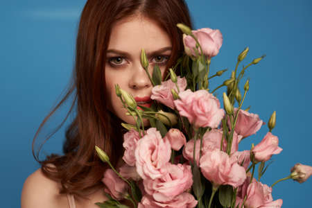 Beautiful woman with a bouquet of pink flowers on a blue background spring model