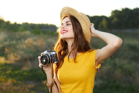 smiling woman holding hand on hat camera nature fresh airの写真素材