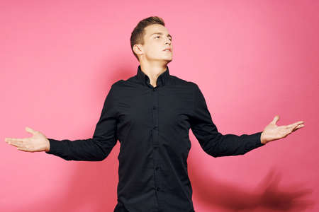 Man in black shirt gestures with hands lifestyle pink isolated background