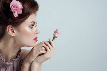 romantic woman with flowers in her hair and vase with pink flower light background tableの写真素材