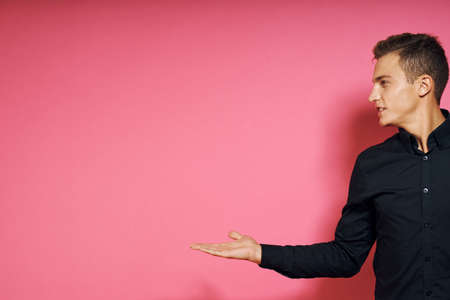 Man in black shirt gestures with hands lifestyle pink isolated backgroundの写真素材