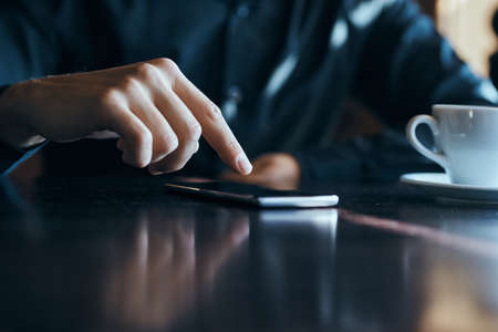 Businessman with mobile phone in cafe at table, cropped viewの写真素材