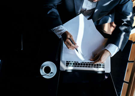 Business man sitting in a cafe in front of a laptop documents coffee cup executive top view technology lifestyleの写真素材