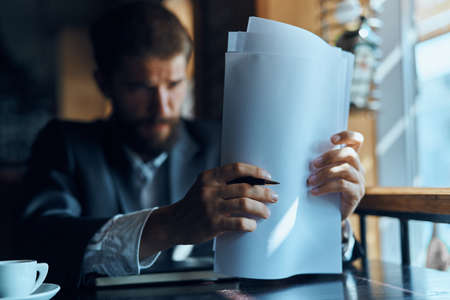 business man sitting at a table in a cafe documents work official coffee cup