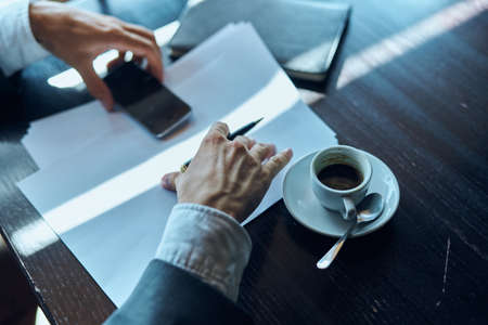 Business man in a cafe documents a cup of coffee on the table official work