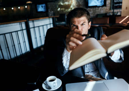 Business man sitting in a cafe in front of a laptop with a cup of coffee work technology lifestyleの写真素材