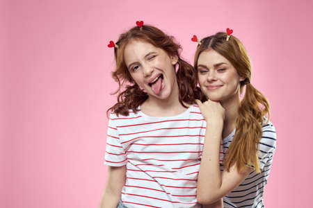 Happy girls with fashionable jewelry on their heads on a pink background fun cropped view of sisters