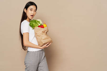 pretty woman in sweatpants and a T-shirt holds a package of groceries in her hands