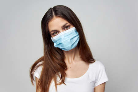 Woman in medical mask on face look ahead lifestyle white t-shirtの写真素材