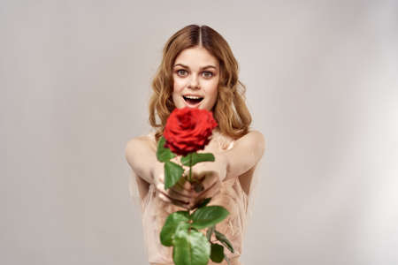 Portrait of a beautiful woman with a red rose on a beige background cropped view of an evening dressの写真素材