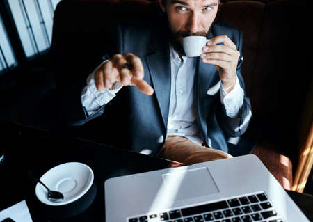 Business man sitting in a cafe in front of a laptop with a cup of coffee work technology lifestyle