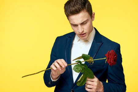 Gentlemen in classic suit on yellow background and red rose romance cropped view model portrait.の写真素材
