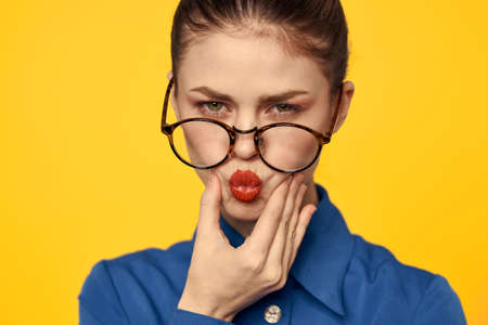 A woman in a blue shirt and glasses with bright makeup on her face is gesturing with her hands Copy Spaceの写真素材